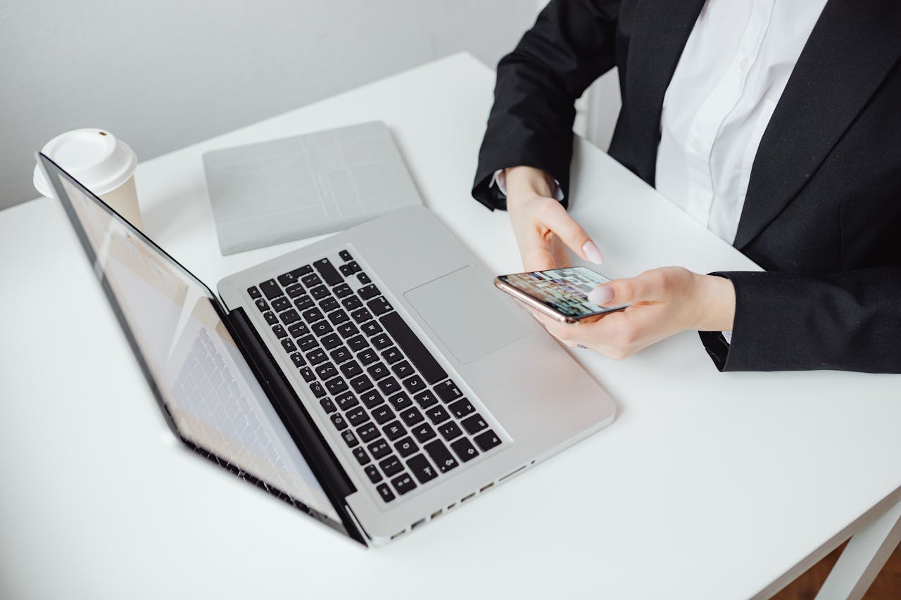 about-us Businesswoman using smartphone at desk with laptop and coffee cup.